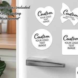 Pode incluir: Autocolantes brancos personalizados em forma de coração, borboleta, círculo e retângulo. Cada autocolante apresenta a palavra "Custom" e espaço para um logótipo, texto e imagem. Os autocolantes são exibidos numa superfície cinzenta.