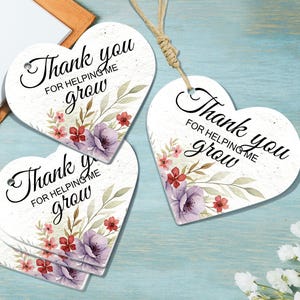 May include: Heart-shaped gift tags with the message "Thank you for helping me grow" in elegant script. The tags feature watercolor floral designs in shades of purple, red, and green, with a rustic twine string.