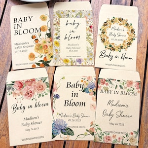May include: A collection of seed packets with floral designs and the text "Baby in Bloom." Each packet is personalized for Madison's baby shower, with the date May 26, 2025, and the words "Wildflower Seeds."