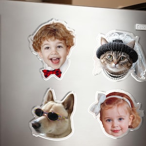 May include: Four fridge magnets with clear outlines. One shows a smiling child with a red bow tie. Another depicts a cat wearing a hat and pearls. A dog wearing sunglasses and a smiling baby girl are also shown.