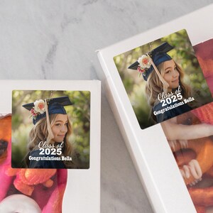 K&ouml;nnte beinhalten: Abschlussfeier-Geschenkanh&auml;nger mit einem Foto einer Person, die eine Abschlusscap und eine Robe tr&auml;gt. Der Aufkleber lautet "Klasse von 2025 Herzlichen Gl&uuml;ckwunsch Bella".