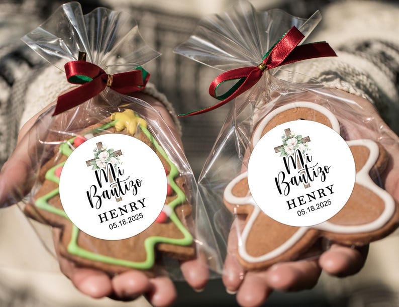 May include: Two gingerbread cookies decorated with white frosting and a round sticker. The sticker has a white background with a cross, green leaves, white flowers, and black text that reads "Mi Bautizo HENRY 05.18.2025".