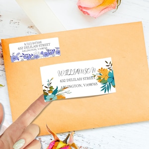 May include: Two white address labels with floral designs on a peach envelope. One label has blue flowers, the other has yellow and teal flowers. The labels display the name "Williamson" and address information.