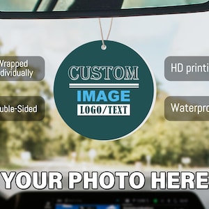 May include: A round, dark teal car air freshener hanging from a rearview mirror. The center features the text CUSTOM IMAGE LOGO/TEXT. Surrounding text boxes state Wrapped Individually, HD printing, Double-Sided, and Waterproof. YOUR PHOTO HERE.