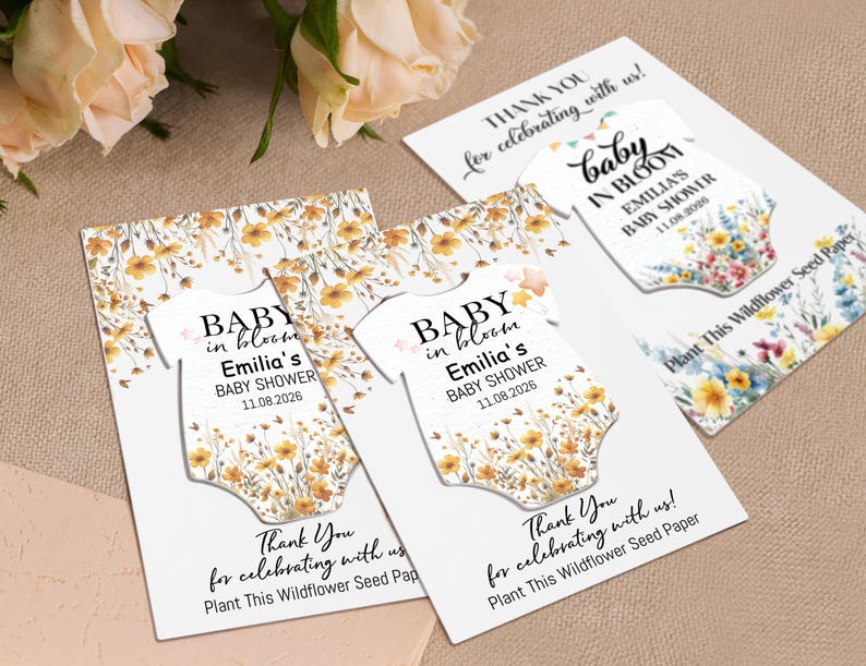 May include: Baby shower seed paper cards with a floral design. The cards feature a baby onesie shape with the text "Baby in Bloom" and event details. The cards are white with a floral pattern and the text "Thank You for celebrating with us!"
