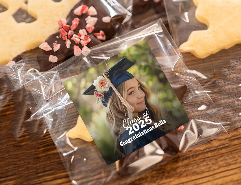 K&ouml;nnte beinhalten: Ein Abschlussgeschenk mit einem personalisierten Foto einer jungen Frau, die eine Abschlusscap und eine Robe tr&auml;gt. Das Geschenk beinhaltet einen Schokoladenkeks in Form eines Sterns und einen Aufkleber mit dem Text "Klasse von 2025 Herzlichen Gl&uuml;ckwunsch Bella".