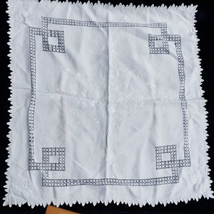 Peut inclure: Nappe en lin blanc avec un motif de broderie florale délicat et un bord festonné. La nappe a une bordure géométrique avec un motif répétitif.