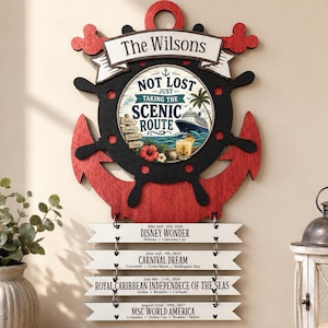 Peut inclure: Une décoration murale en bois représentant une ancre et une barre de navire rouges et noires. Le centre présente un graphique sur le thème des croisières avec le texte "Not Lost Just Taking The Scenic Route". Quatre étiquettes listent des détails.