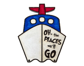 May include: A wooden ship-shaped sign with a blue and red painted design. The sign says "Oh, the places we'll go".
