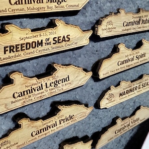 May include: A collection of wooden cruise ship souvenirs featuring the names of different ships and their itineraries. The ships are all in the same style, with a simple outline of a cruise ship and the name of the ship and its itinerary printed below.