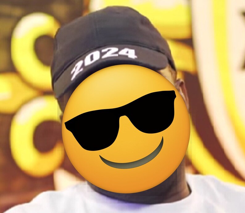 May include: A black cap with the year "2024" printed in white. The image features a yellow emoji with sunglasses covering the face. The background is blurred with yellow and white shapes.