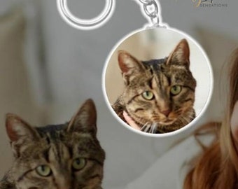 Op de afbeelding: Een ronde sleutelhanger met een foto van een tabbykat. De sleutelhanger is zilverkleurig en heeft een sleutelring.