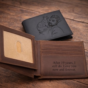 May include: Two leather wallets, one open and one closed, on a wooden surface. The open wallet is brown with a clear ID window and text that reads, "After 19 years, I still do. Love you now and forever." The closed wallet is black with an engraved image.