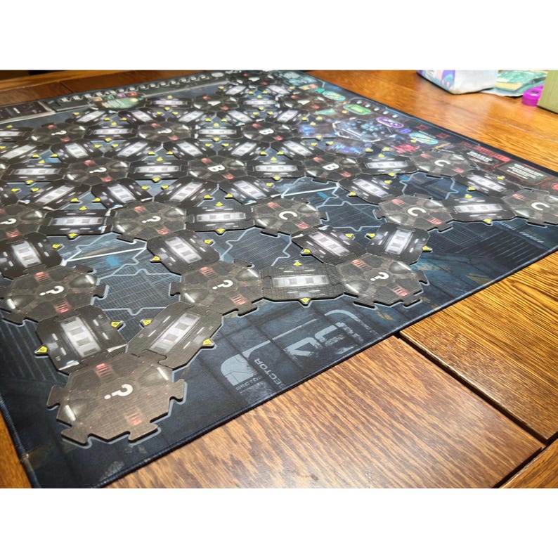 May include: A board game with a futuristic design. The game board is dark with a grid of hexagonal tiles. Each tile has a question mark and a detailed design. The game is set on a wooden table.