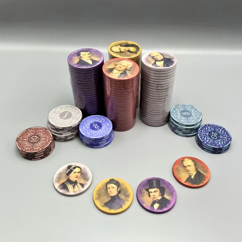 Op de afbeelding: Stapels paarse, rode en grijze pokerchips met afbeeldingen van historische figuren. Er zijn ook individuele chips met afbeeldingen van historische figuren in verschillende kleuren, waaronder goud, paars en rood.