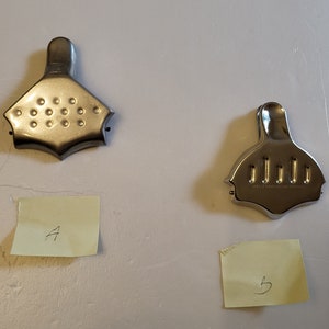 May include: Two silver metal citrus juicers, one with a scalloped edge and a grid of holes, the other with a smooth edge and a row of holes. The juicers are labeled A and B on yellow sticky notes.