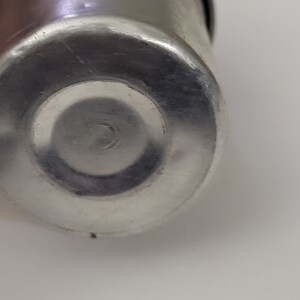 May include: Close-up of the bottom of a silver metal container. The container has a smooth, shiny surface.