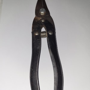 May include: Black metal wire cutters with a spring and a silver screw. The wire cutters have a black rubber handle and the text "HITCO" is visible on the metal.