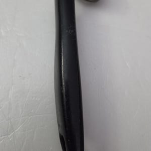 May include: A black can opener with a black handle and a silver, circular cutting mechanism. The handle is smooth and ergonomic, with a hole at the end for hanging. The can opener is designed for easy use.