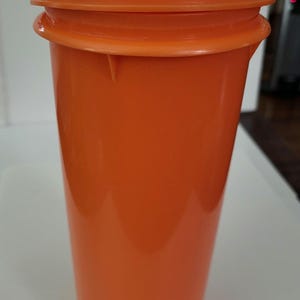 May include: Orange plastic pitcher with a lid and a spout. The lid has a handle.