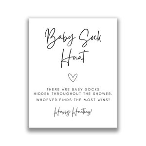 May include: A white sign with black text that says "Baby Sock Hunt" with a heart symbol. The text below says "There are baby socks hidden throughout the shower. Whoever finds the most wins! Happy Hunting!"