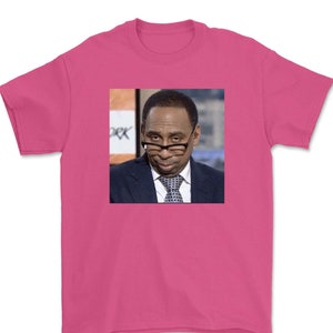 May include: A pink t-shirt with a picture of a man wearing a suit and tie. The man is looking to the side and has a serious expression on his face.