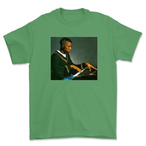May include: A green t-shirt with a photo of a man wearing headphones and playing a keyboard.