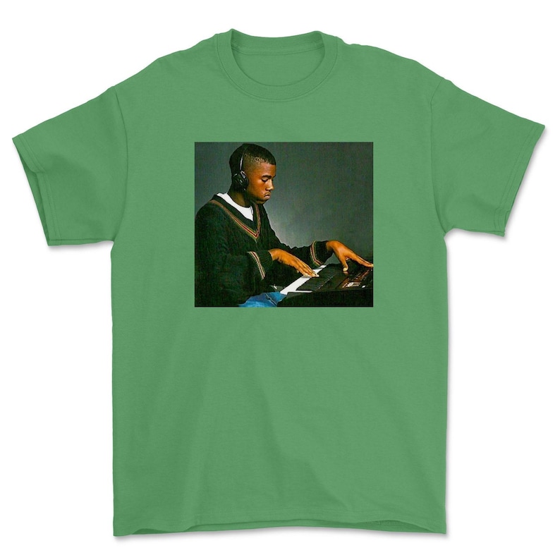 May include: A green t-shirt with a photo of a man wearing headphones and playing a keyboard.