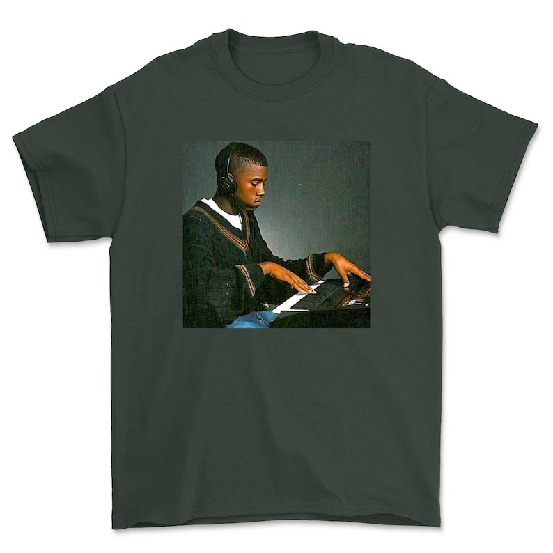 May include: A dark green t-shirt featuring a black and white photo of a man wearing headphones and playing a keyboard.