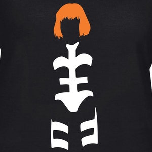 May include: A black t-shirt with a white silhouette of a woman with orange hair. The woman is wearing a white outfit with a geometric design.