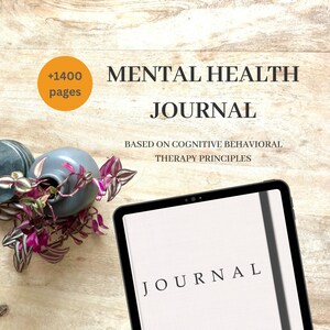 May include: A mental health journal with the word "JOURNAL" on the cover. The journal is based on cognitive behavioral therapy principles and has over 1400 pages. A small vase with purple and green plants sits to the left of the journal.