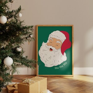 May include: A framed print featuring a vintage illustration of Santa Claus with a red hat and white beard against a green background. The words "Ho Ho Ho" are written in white. The print is in a wooden frame.