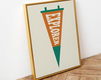 May include: A framed wall art print featuring a vertical pennant design. The pennant is orange with a dark green top and bottom tip, displaying the word EXPLORER in large white capital letters. The frame is a thin, metallic gold colour.