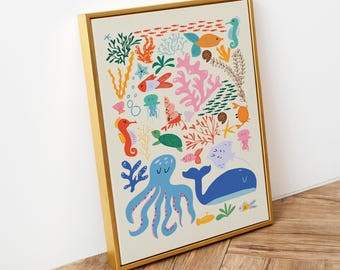 May include: A framed wall art print featuring a colourful illustration of various marine life including a blue octopus, a blue whale, a green sea turtle, seahorses, coral, and small fish scattered across a light cream background in a gold frame.