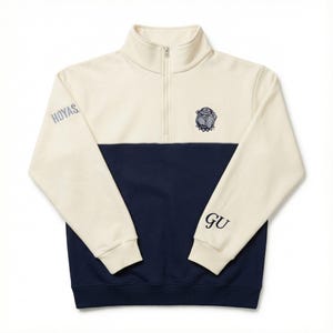 May include: Cream and navy blue quarter-zip sweatshirt. The top half is cream, the bottom half is navy. Features the word "HOYAS" on the left sleeve and "GU" on the right sleeve. A bulldog logo is embroidered on the chest.