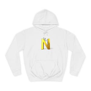 Op de afbeelding: Witte hoodie met een voorzak. Het ontwerp toont een gouden letter "N" met een klein wit figuur dat erop klimt. De hoodie is gemaakt van een zacht materiaal.