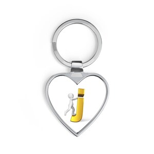 Può includere: Portachiavi a forma di cuore argentato con una piccola figura che spinge la lettera "J" dorata. Il portachiavi ha un anello nella parte superiore per attaccare le chiavi. Il design è semplice e moderno, adatto per uso personale o come regalo.