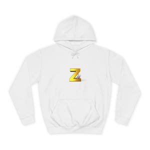 May include: A white hoodie with a gold-coloured letter "Z" in the centre. The "Z" has a 3D effect with a shadow. The sweatshirt has a front pocket and a drawstring hood.