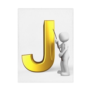 Op de afbeelding: Een gouden letter "J" staat prominent op een witte achtergrond, met een klein wit figuur dat er met een dunne, donkere staaf naar wijst. De letter heeft een glanzend, metallic uiterlijk.