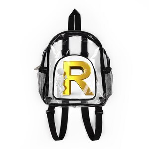 Op de afbeelding: Transparante rugzak met zwarte randen, banden en mesh zijvakken. Het heeft een gouden letter "R" met 3D-effect en een klein wit figuur. De rugzak heeft een handvat en verstelbare schouderbanden.
