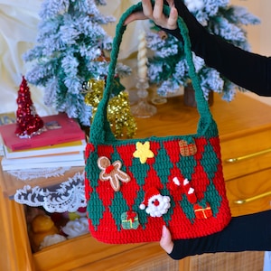 May include: A red and green crocheted Christmas-themed tote bag with a gingerbread man, a star, a candy cane, a Santa Claus, and a gift box.