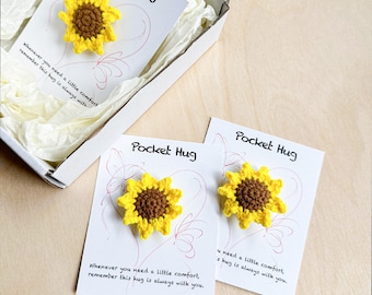 May include: Two small crocheted sunflower pocket hugs on white cards with the text "Pocket Hug" and "Whenever you need a little comfort, remember this hug is always with you."