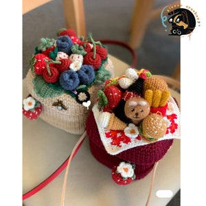 May include: Two crocheted bags, one with a red and white picnic theme and the other with a strawberry and blueberry theme. The picnic bag features a crocheted bear, a burger, and french fries. The strawberry and blueberry bag has a crocheted bee on the side.
