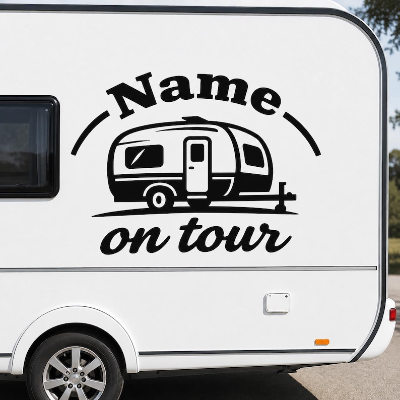 May include: Black and white decal on a white camper van. The decal features a stylized camper with the words "Name" above and "on tour" below. The camper van has a black tire and a window.
