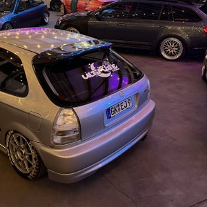 May include: A silver Honda Civic with a black rear spoiler and a "102 Ultimate Crew" sticker on the rear window. The car has a number plate that reads "GK EJ9".