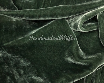May include: Close-up of a deep green velvet fabric with a subtle sheen. The fabric is soft and luxurious, with a smooth texture. The fabric is folded and draped, showing its drape and flow.