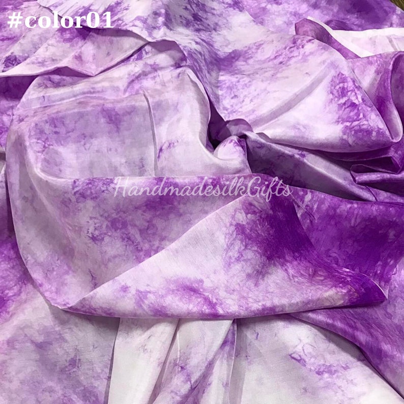 May include: A close-up of a flowing fabric with a tie-dye pattern in shades of purple and white. The fabric is draped, showing folds and textures. The text "#color01" is in the top left corner, and "HandmadesilkGifts" is in the bottom right.