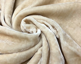 May include: Close-up of a soft, beige velvet fabric. The fabric is draped and folded, showcasing its texture and drape.