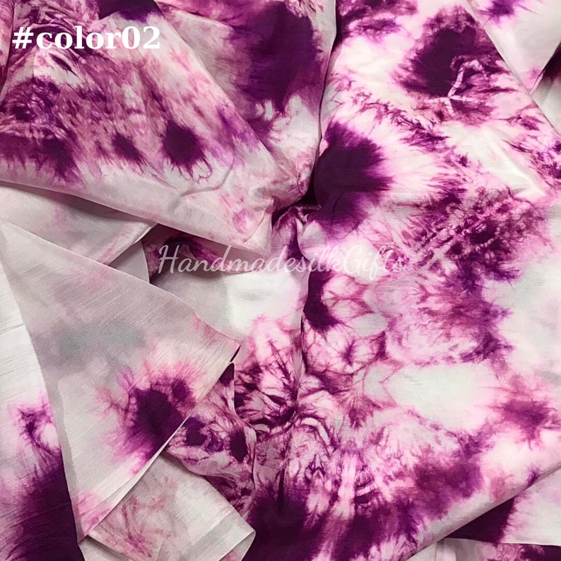 May include: Close-up of a fabric with a tie-dye pattern in shades of purple and white. The fabric has a soft, flowing appearance. The text "#color02" is in the top left corner. The text "HandmadesilkGifts" is in the center.
