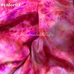 May include: A close-up of a silk fabric with a vibrant tie-dye pattern in shades of pink, red, and orange. The text "#color03" is in the top left corner, and "Handmadesilk Gifts" is in the center.